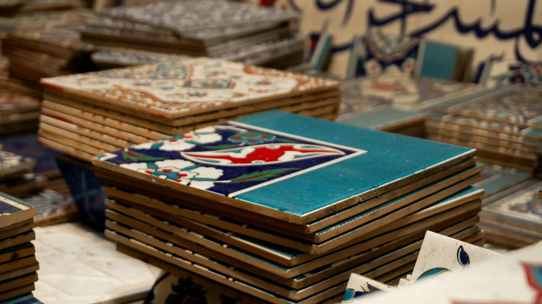 Pilas de azulejos cerámicos decorados con distintos motivos geométricos y florales apilados en un taller